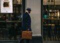 man in black suit jacket and blue hat standing in front of store