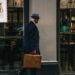 man in black suit jacket and blue hat standing in front of store