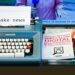 a blue typewriter sitting on top of a desk next to a tv