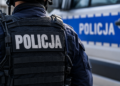 Close-up of a Polish police officer in tactical uniform beside a police vehicle
