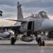 Swedish JAS 39 Gripen fighter aircraft on an airbase apron with Polish and Swedish flags