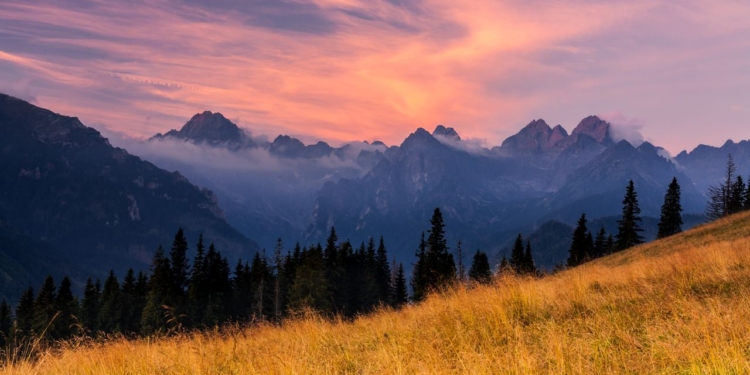Beautiful sunset over the Tatra Mountains with a view of misty peaks and colorful sky.