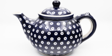 A cobalt-blue Bolesławiec ceramic teapot with white circular decorative motifs, photographed by Jacek Halicki, 2023.