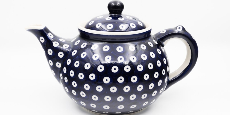 A cobalt-blue Bolesławiec ceramic teapot with white circular decorative motifs, photographed by Jacek Halicki, 2023.