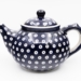 A cobalt-blue Bolesławiec ceramic teapot with white circular decorative motifs, photographed by Jacek Halicki, 2023.
