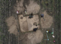 Overhead photograph of four archaeological researchers examining an excavation trench in a field at Gródek, eastern Poland. Image from the Stanisław Staszic Museum in Hrubieszów.