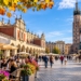 Editorial illustration of Kraków Main Market Square with St Mary's Basilica, Cloth Hall, outdoor cafés and people in an autumn city scene.