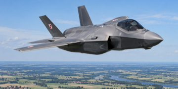 Digitally created illustration of a Polish F-35A Husarz fighter flying above green fields and a river in Poland