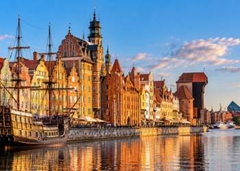 AI-generated illustration of a Gdańsk-inspired historic Baltic waterfront featuring colourful buildings, a sailing ship and a timber harbour crane; not an authentic photograph.