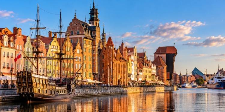 AI-generated illustration of a Gdańsk-inspired historic Baltic waterfront featuring colourful buildings, a sailing ship and a timber harbour crane; not an authentic photograph.