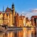 AI-generated illustration of a Gdańsk-inspired historic Baltic waterfront featuring colourful buildings, a sailing ship and a timber harbour crane; not an authentic photograph.