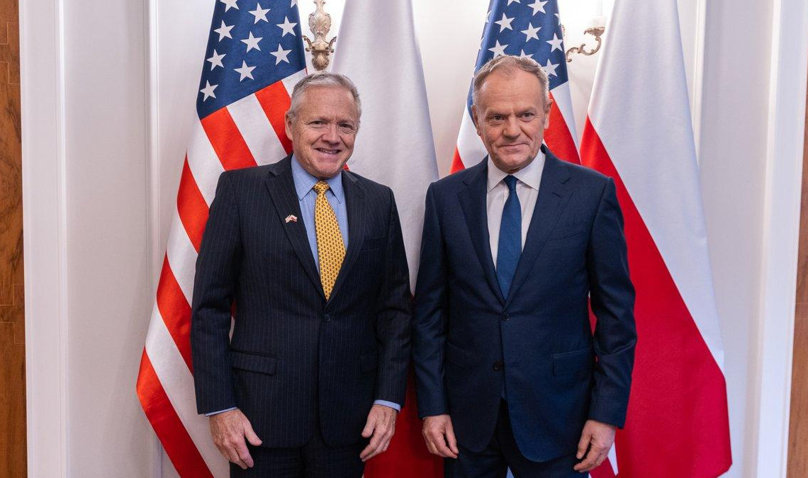 US Ambassador Thomas Rose and Prime Minister Donald Tusk pose together before US and Polish flags at a meeting in Warsaw in December 2025.