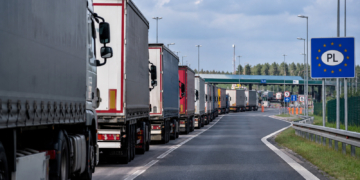 Digitally generated illustration showing a queue of freight lorries approaching a fictionalised Polish border checkpoint.
