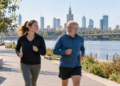 Editorial illustration of two Warsaw joggers of different ages running beside the Vistula, with the Warsaw skyline and a bridge in the background.