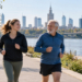 Editorial illustration of two Warsaw joggers of different ages running beside the Vistula, with the Warsaw skyline and a bridge in the background.