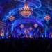 AI-generated editorial illustration of a jazz ensemble performing in an underground salt chamber illuminated with blue lighting and chandeliers, with an audience in the foreground