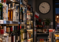 Alcohol bottles in a Polish shop at night with a wall clock after 10 p.m.