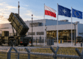 Editorial image of a European defence factory under air-defence protection with Polish, NATO and EU flags