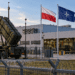 Editorial image of a European defence factory under air-defence protection with Polish, NATO and EU flags