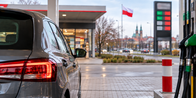 Car at a petrol station in Poland with fuel pumps and a Polish flag