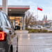 Car at a petrol station in Poland with fuel pumps and a Polish flag