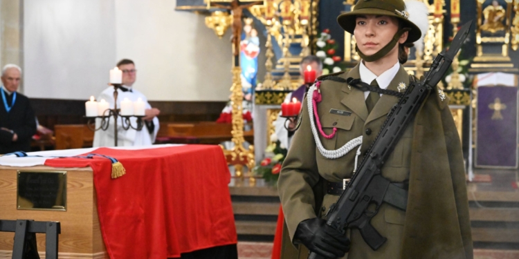 Polish military honour guard beside General Józef Giza's flag-draped coffin in a church during the 2026 reburial ceremony