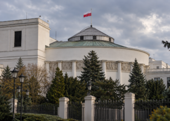 Digitally created architectural illustration of the Polish Sejm parliament building in Warsaw beneath an overcast sky, with the Polish flag flying