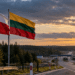 Polish and Lithuanian flags beside a border road, illustrating evacuation planning between Lithuania and Poland