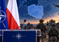 NATO podium beside Polish and NATO flags with a highlighted map of Poland and allied military forces