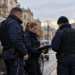 Digitally created illustration of three police officers beside a dark vehicle on a Polish street, unrelated to the reported banking-fraud operation