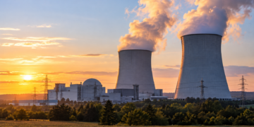 Illustration of a proposed nuclear power station with cooling towers at sunset; not an existing Polish plant.