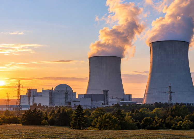 Illustration of a proposed nuclear power station with cooling towers at sunset; not an existing Polish plant.