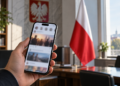 Digitally created illustration of a smartphone with a blurred social-media feed in a generic office, with a Polish flag in the background.