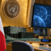 Polish flag in a UN-style conference chamber beside a digital artificial intelligence governance display