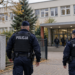 Digitally created editorial image of two Polish police officers approaching a school entrance during an autumn safety patrol