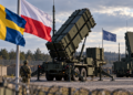 Patriot air-defence launcher with Swedish, Polish and NATO flags at a generic military site