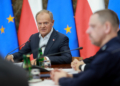 Government officials seated at a conference table with Polish and European Union flags in the background
