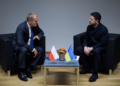 Donald Tusk and Volodymyr Zelenskyy seated opposite each other during talks with Polish and Ukrainian flags between them