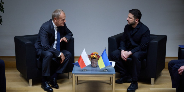 Donald Tusk and Volodymyr Zelenskyy seated opposite each other during talks with Polish and Ukrainian flags between them