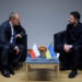 Donald Tusk and Volodymyr Zelenskyy seated opposite each other during talks with Polish and Ukrainian flags between them