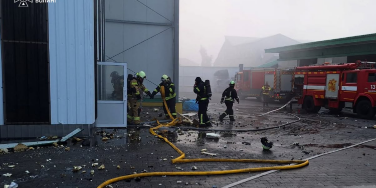 Firefighters and fire engines amid debris and smoke at an industrial site in Ukraine's Volyn region.