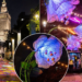 Editorial photo collage showing the illuminated Palace of Culture and Science, projected colours on a park walkway and glowing floral light installations in Warsaw; not a photograph of the 15 October opening ceremony.