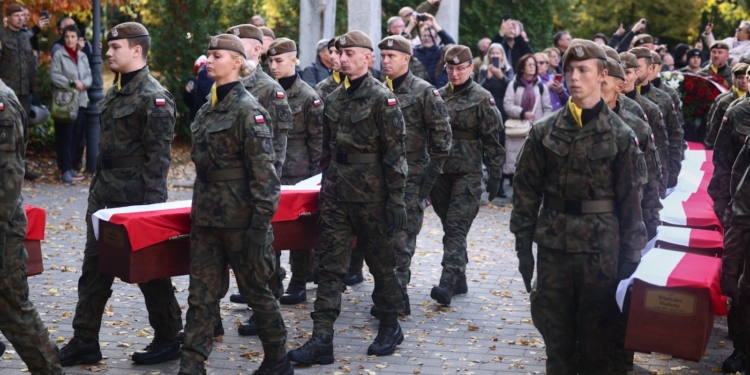 Polish soldiers carry flag-draped coffins during the state funeral for 49 victims of communist repression at Wrocław's Osobowicki Cemetery.