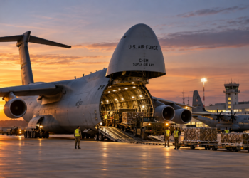 Digitally generated illustration of a US C-5M transport aircraft with its cargo bay open, ground crew and military vehicles on an airfield; not the future Wrocław facilities.