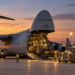 Digitally generated illustration of a US C-5M transport aircraft with its cargo bay open, ground crew and military vehicles on an airfield; not the future Wrocław facilities.